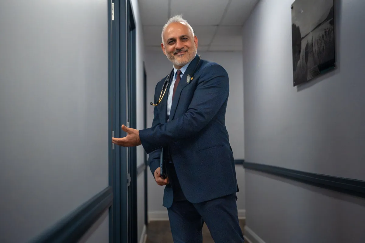Dr. Suresh Malik holding an exam room door open in a Quality Primary Care Associates office