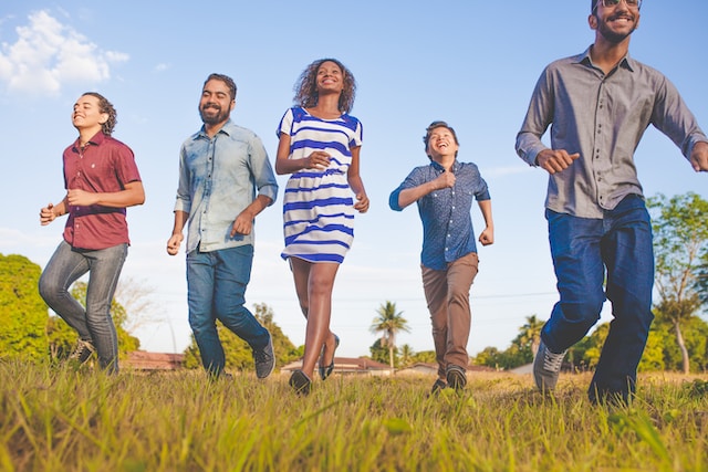 Group of people walking in a grassy field.