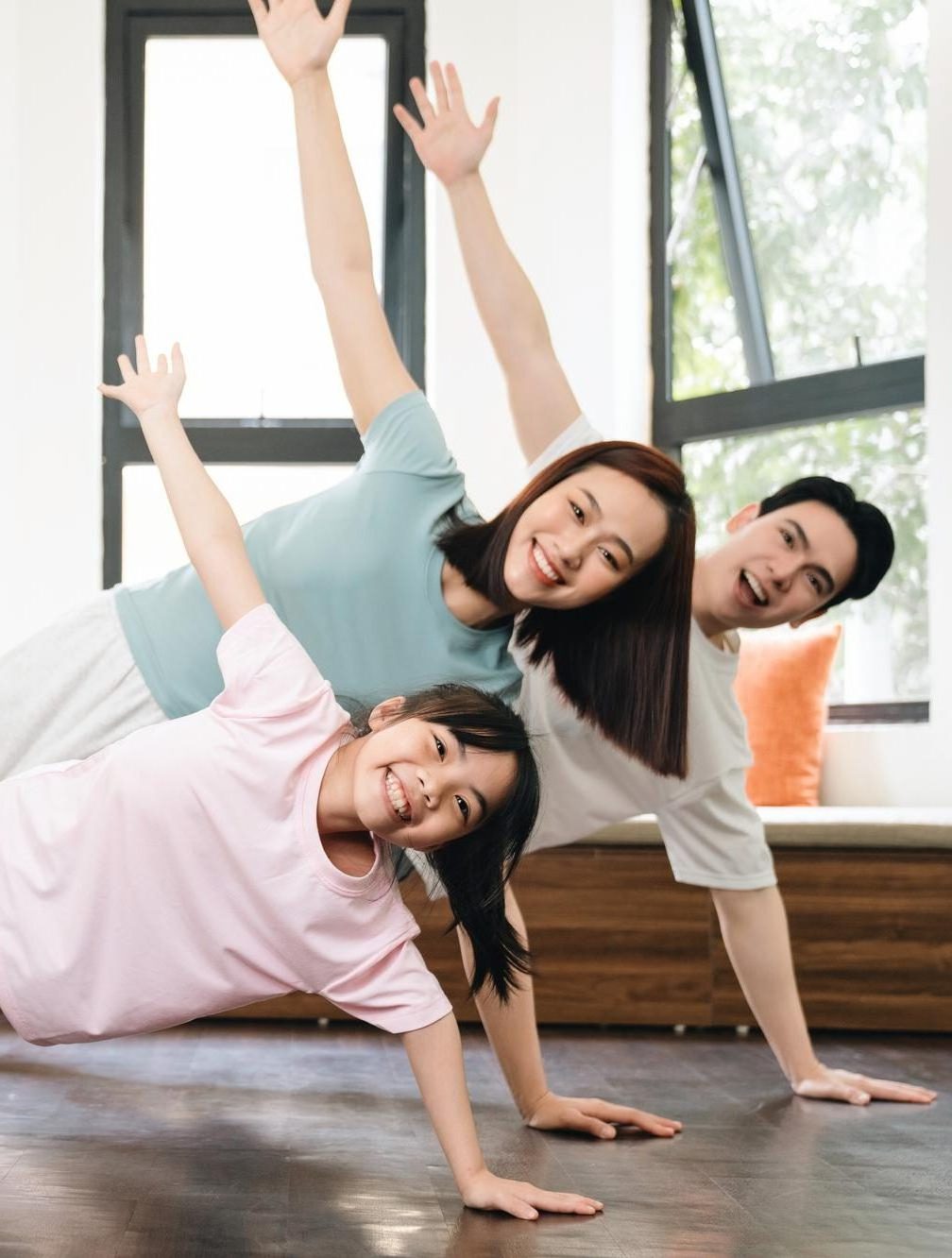 Family doing side plank exercise indoors, smiling.